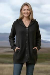 Woman outdoors in a dark knitted cardigan with pockets, smiling at the camera.